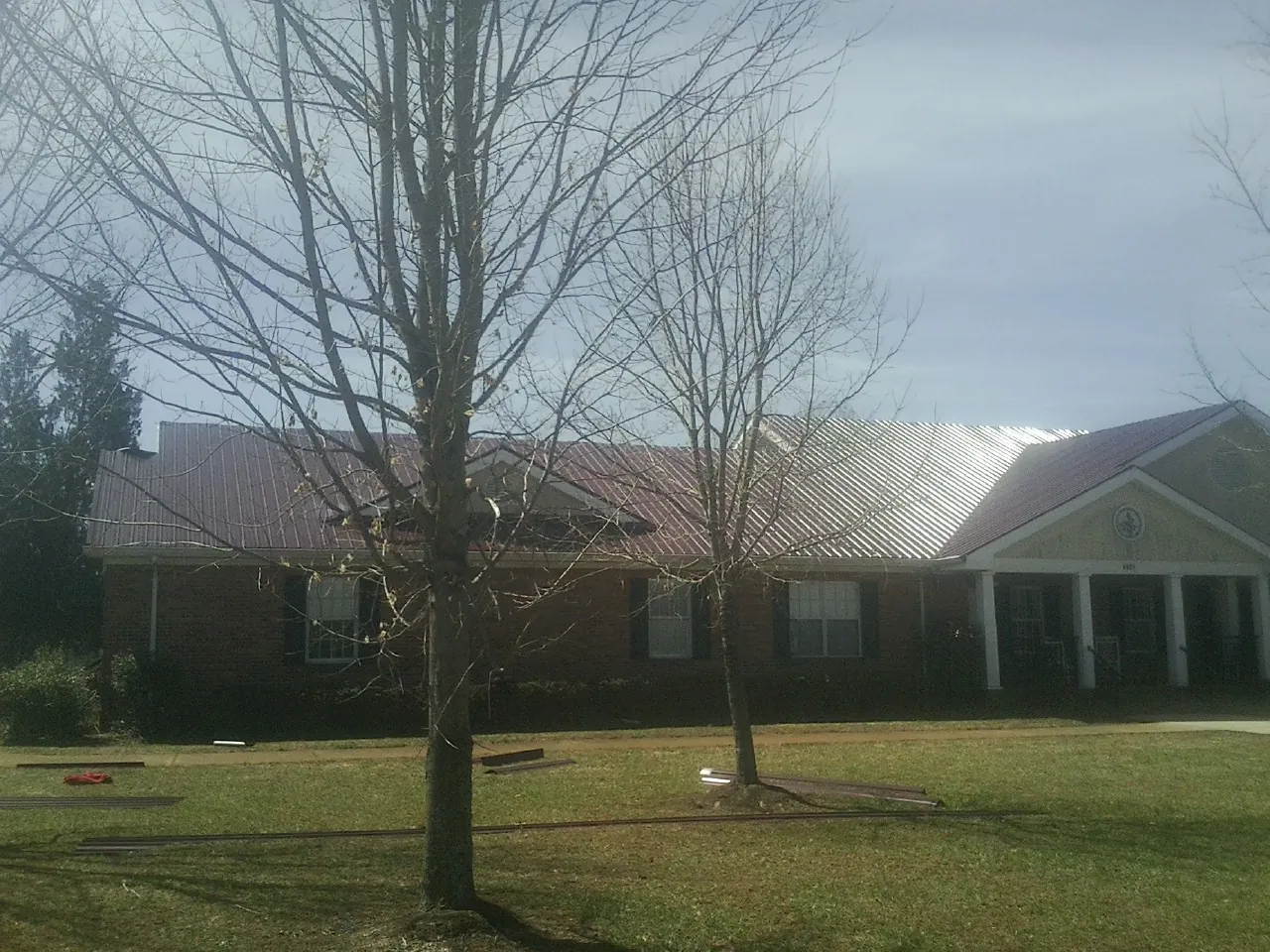 Red metal roof on a brick building seen from the front lawn in Onsted