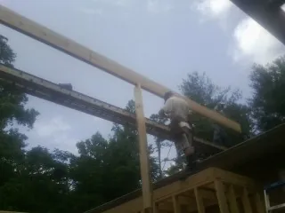 Carpenter setting a ridge beam over a new addition frame — Ice Dam Removal by Roofing Brothers in Onsted