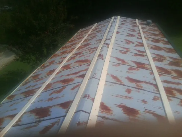 Rusted metal roof panels with new wood purlins before replacement — Storm Damage Roof Repair in Onsted by Roofing Brothers