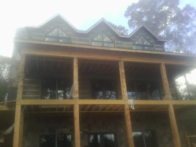 Dormers and porch framing on a large log home under construction — Roof Coating work by our crew in Onsted