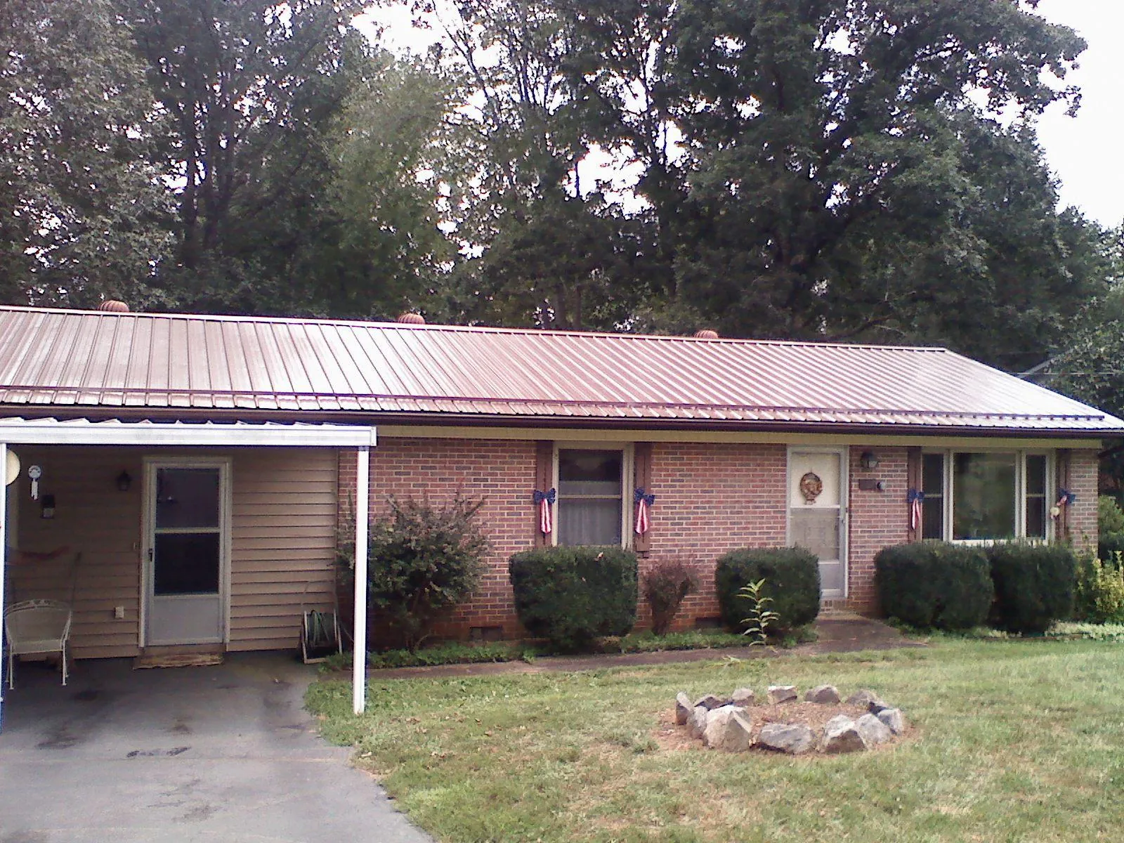 Bronze metal roof and carport on a brick ranch home — Roof Repair work by our crew in Onsted