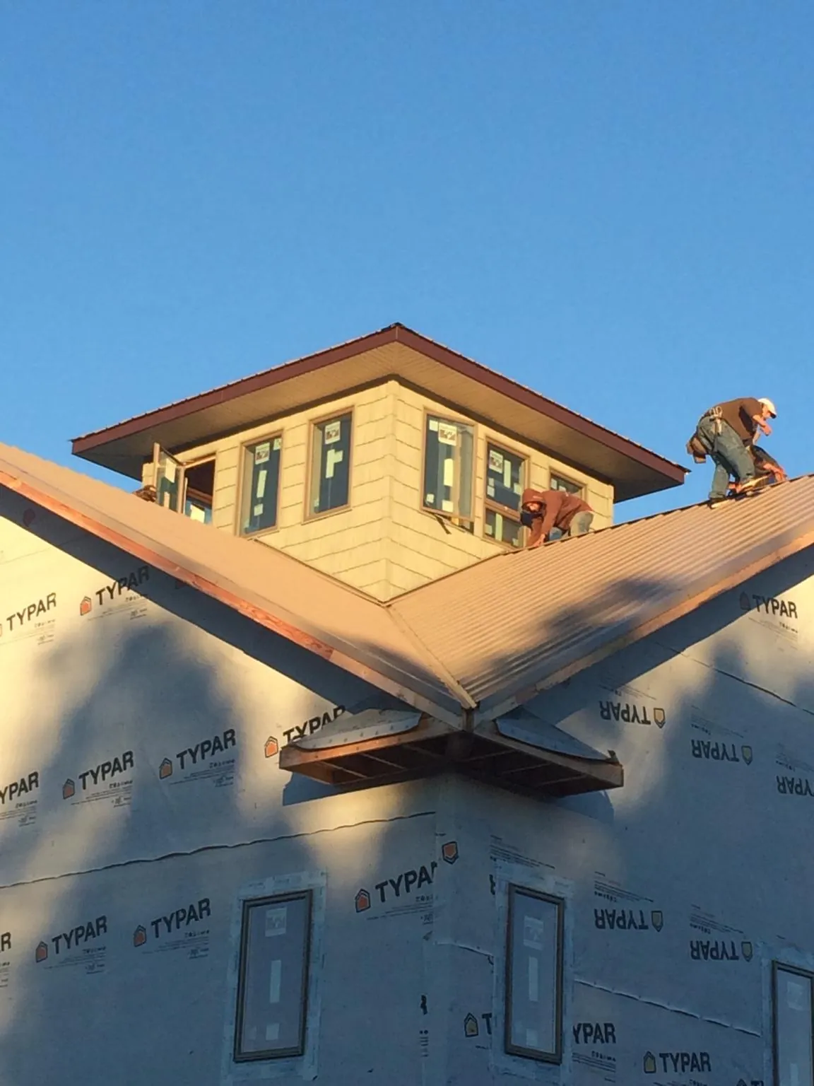 Roofers working around a rooftop cupola on a new metal roof at sunset — Roof Waterproofing in Onsted by Roofing Brothers